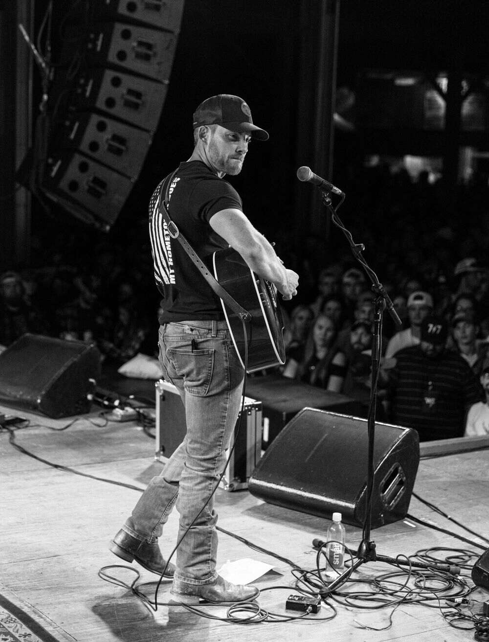 Side profile of Steven Cali singing at the microphone, crowd behind him