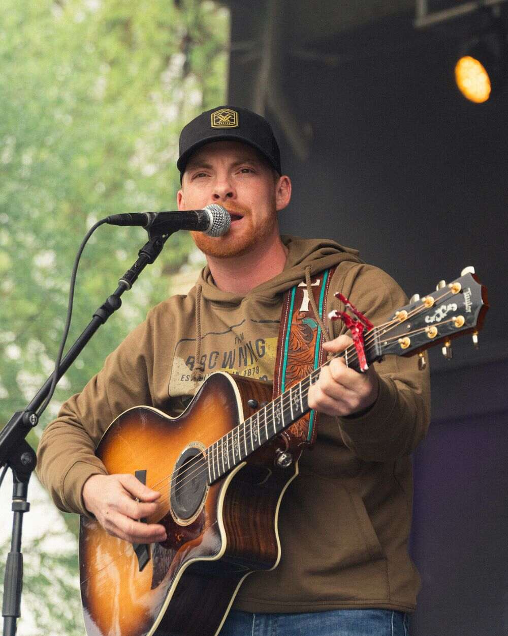 Steven Cali performing outdoors with a sunburst acoustic guitar